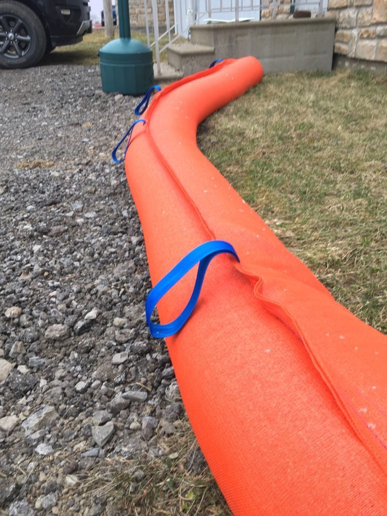 StormCatcher weighted sediment filter tube installed on a gravel shoulder